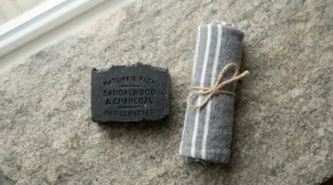 A flat lay arrangement featuring a charcoal soap bar for men and a cotton flannel