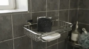 A charcoal soap bar for men placed on a minimalist stainless steel shower rack